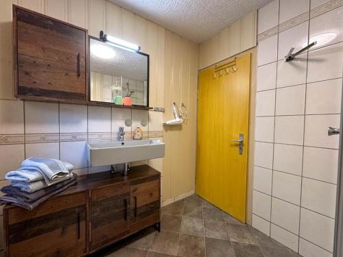 a bathroom with a sink and a yellow door at Knusperhäuschen in Engenstein
