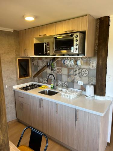 a kitchen with a sink and a microwave at Cabañas y Lodges de Playa Ritoque RITOKAZO in Quintero