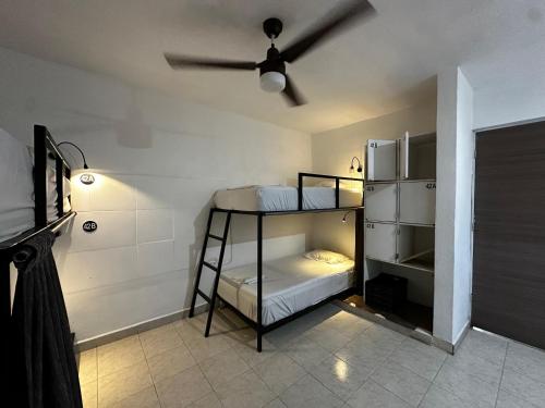 a room with two bunk beds and a ceiling fan at The Soul Hostal in Playa del Carmen