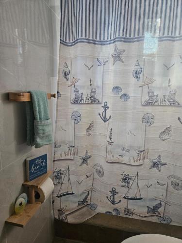 a bathroom with a shower curtain with a drawing of the ocean at Sea view house in Utila