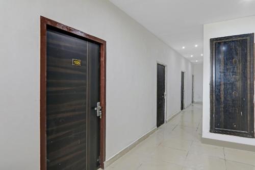 a hallway with a black door and white walls at Hotel O Rudra Palace Near Phoenix United Lucknow in Alambagh