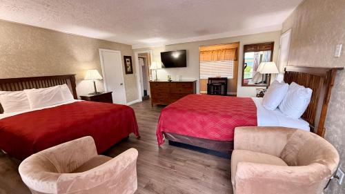 a hotel room with a red bed and two chairs at Sage N Sand Motel in Moses Lake