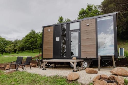 a tiny house on a trailer with a table and chairs at 8 Farm Macadamia Plantation 2 by Tiny Away in Cumbalum