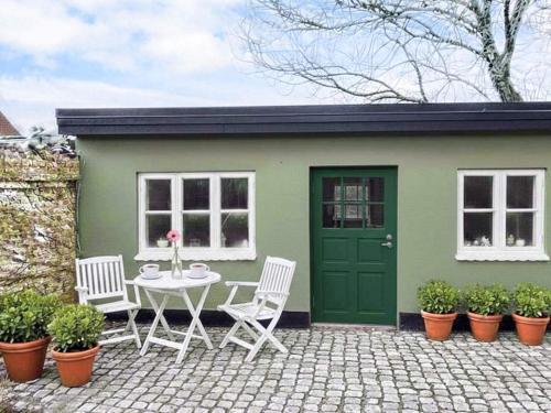 a table and chairs in front of a green shed at 4 star holiday home in Ringkøbing in Ringkøbing