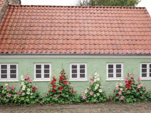 a green house with flowers in front of it at 4 star holiday home in Ringkøbing in Ringkøbing
