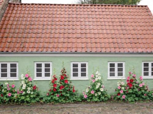 a green house with flowers in front of it at 4 star holiday home in Ringkøbing in Ringkøbing