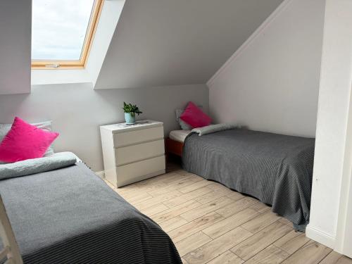 two beds in a small room with pink pillows at Agritourism by the sea in Ładzin