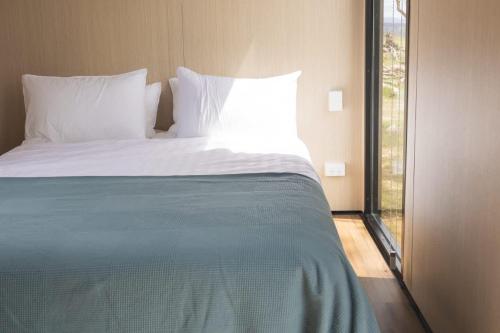 a bed with white sheets and pillows in a bedroom at Beckford Tiny House 1 by Tiny Away in Good Hope