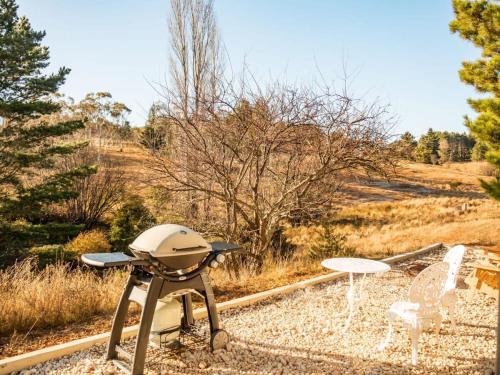 a barbecue grill and two chairs in a field at Blue Gum at Langdale 1 by Tiny Away in Bungendore