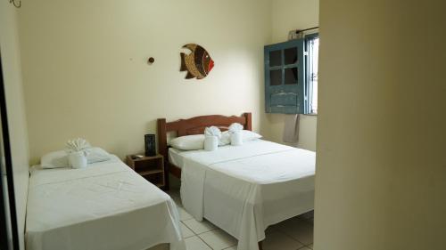 a bedroom with two beds with white sheets at Pousada Casa do Professor in Barreirinhas