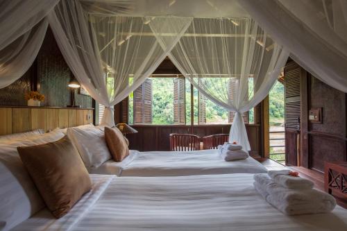 a bedroom with two beds with drapes at The Luang Say Lodge in Pakbeng