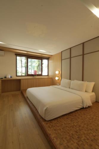 a large white bed in a room with a window at Lavana Villa by Raminten in Yogyakarta
