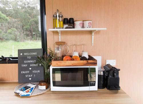 a microwave sitting on top of a counter with a sign at Gumnut by Tiny Away in Kangaroo Valley