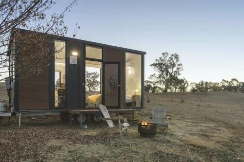 a black tiny house with two chairs and a grill at The High Country Views Escape by Tiny Away in Table Top