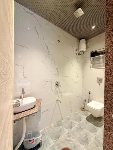 a bathroom with a marble wall with a sink and a toilet at Saiprasad suite & stay in Ellora