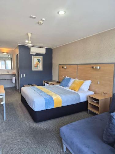 a hotel room with a large bed and a couch at Landmark Manor in New Plymouth