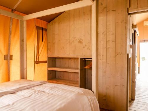 a bedroom with a bed and wooden walls at Glamping Lodge in Westerland
