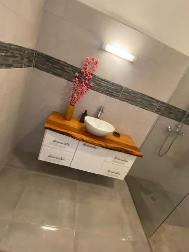 a bathroom with a sink and a vase of flowers on a counter at Grand appartement ventilé in Morne-à-lʼEau
