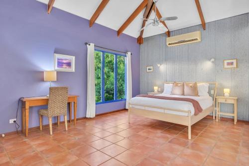 a bedroom with a bed and a table and a desk at The Zoo House in Broome