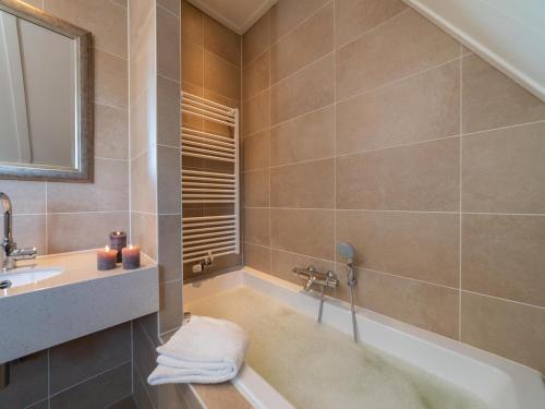 a bathroom with a bath tub and a sink at Zwembadvilla in Colijnsplaat