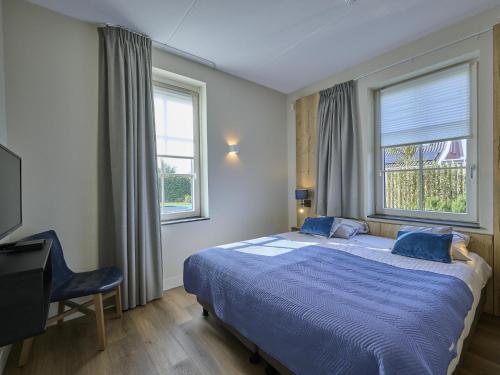 a bedroom with a bed with a blue comforter and two windows at SeaLuxe Residence 27C in Colijnsplaat