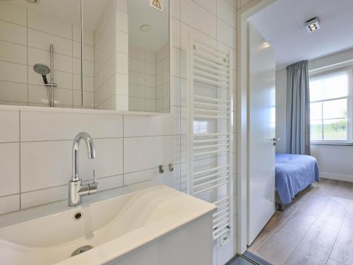 a white bathroom with a sink and a bedroom at SeaLuxe Residence 27C in Colijnsplaat