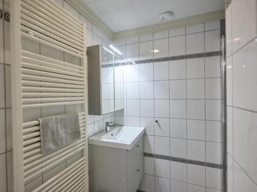 a white tiled bathroom with a sink and a shower at t Kaatsheuveltje 2 in Kaatsheuvel