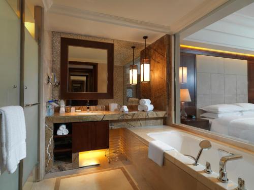a bathroom with a bath tub and a bed at Sheraton Changbaishan Resort in Fusong