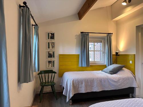 a bedroom with a bed and a window and a chair at Op de Beemd in Zeeland