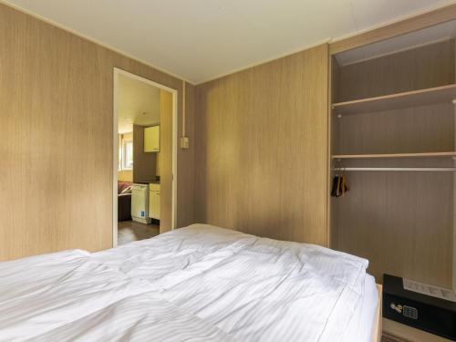 ein Schlafzimmer mit einem weißen Bett und einem Kleiderschrank in der Unterkunft Easy Chalet in Vessem