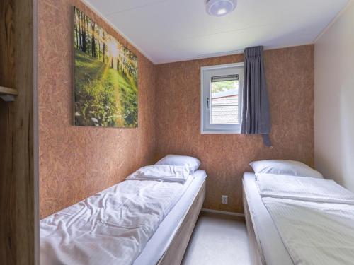 two beds in a small room with a window at Woodchalet in Vessem