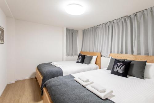 two beds in a room with white and black at 金洲House 懿-下寺 in Osaka