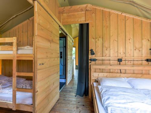 a bedroom with two bunk beds in a room with wooden walls at Safaritent 6 in Vessem