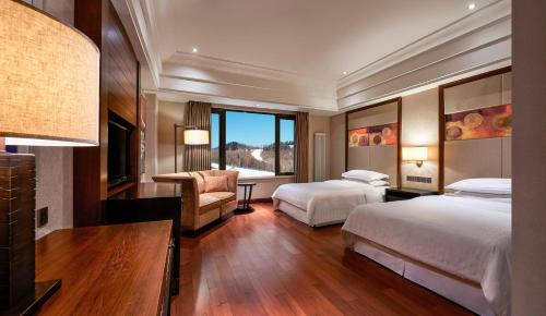 a hotel room with two beds and a desk at Sheraton Changbaishan Resort in Fusong