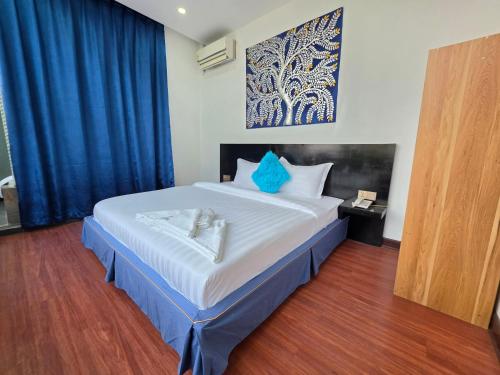 a bedroom with a large white bed with blue pillows at Jason Residencia One Hotel in Phnom Penh