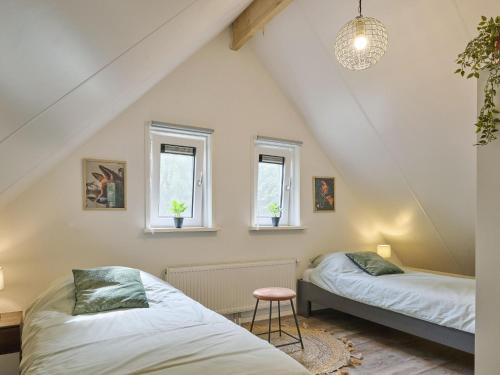 two beds in a attic room with two windows at De Linde in Nunspeet