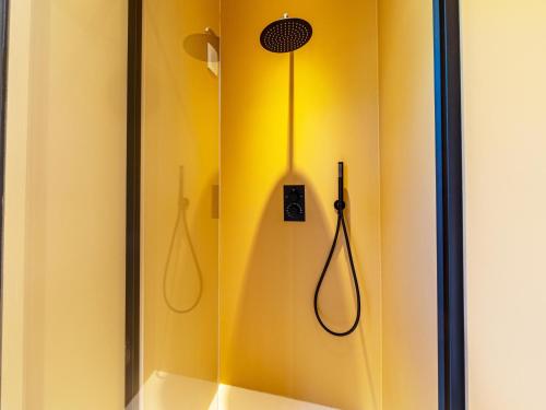 a shower with a yellow wall with two hoses at Mos in Nunspeet