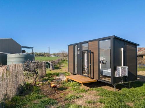 a black tiny house sitting in a field at Starry Night Farmstay by Tiny Away in Forbes
