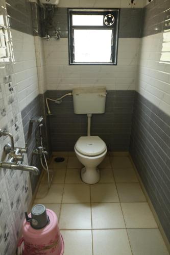 a small bathroom with a toilet and a window at Blue Diamond Dapoli in Murūd