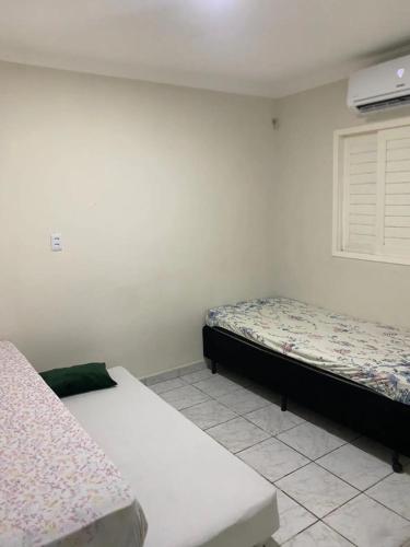 a bedroom with two beds and a window at Casa ampla e confortável in Mossoró