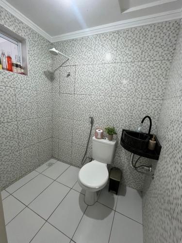 a white bathroom with a toilet and a sink at Casa ampla e confortável in Mossoró
