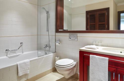 a bathroom with a toilet and a tub and a sink at Corinthia Budapest in Budapest