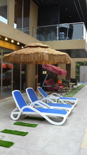 a group of lounge chairs and an umbrella at Bianca Villa in Al Rama