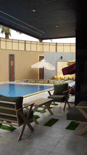 a pool with chairs and a table and an umbrella at Bianca Villa in Al Rama