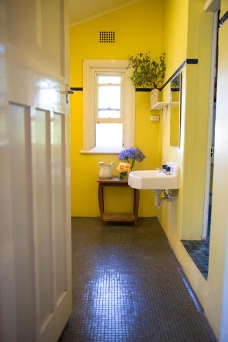 a yellow bathroom with a sink and a window at Boorowa Hotel in Boorowa