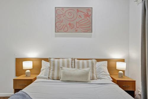 ein Schlafzimmer mit einem Bett, zwei Nachttischen und zwei Lampen in der Unterkunft Shell Escape in Broome
