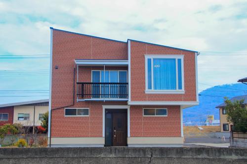 a red brick house with a door and a balcony at Taisho Roman-style Private Villa with Original Japanese Art 日本画原画の一棟貸し M's Lumos in Marugame
