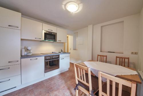 a kitchen with white cabinets and a table in a room at Ski & Bike Appartements Forsthaus in Saalbach Hinterglemm