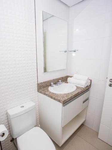 a bathroom with a white toilet and a sink at Residencial Villa Lobos in Torres