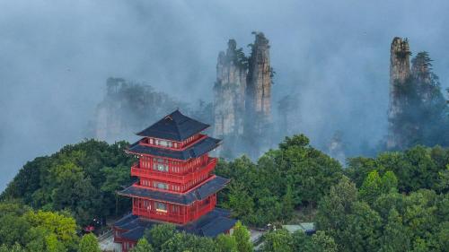 a pagoda in the middle of a forest with smoke at Zhangjiajie Cloudscape Villa - New Hotel, Free Private Car Rides to South & East Gates of Zhangjiajie National Forest Park,Free Private Car Rides to & from Airport,Chinese-Western Breakfast, Coffee, Tea & Fruit, Free Laundry & Dryer, Ticket Guidan in Zhangjiajie
